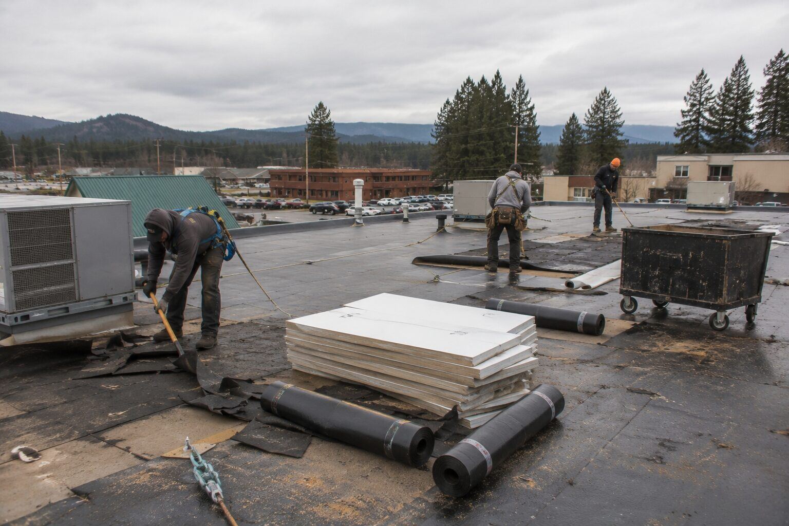 Roofing Rehab crew removing old membrane on a flat commercial roof