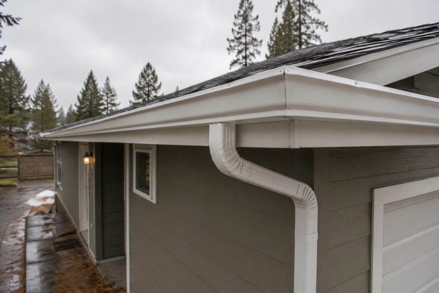 Finished seamless gutter and downspout installed along a roofline